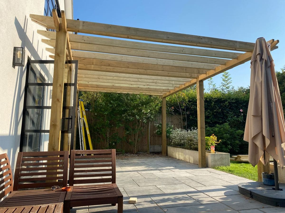 Timber pergola over a garden patio with seating