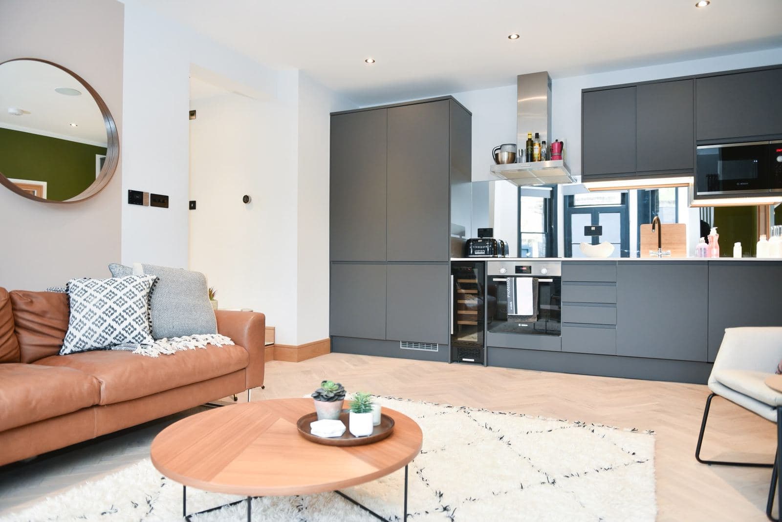 Finished living room with a leather sofa and open kitchen behind