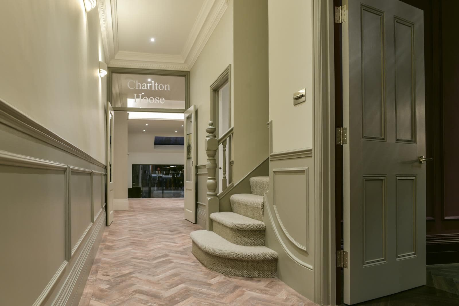 Hallway with wall panelling, herringbone floor and a staircase