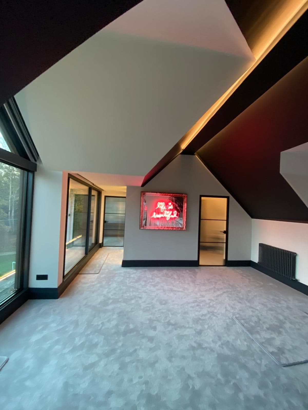 Finished open top floor room with a pitched ceiling and glazed doors