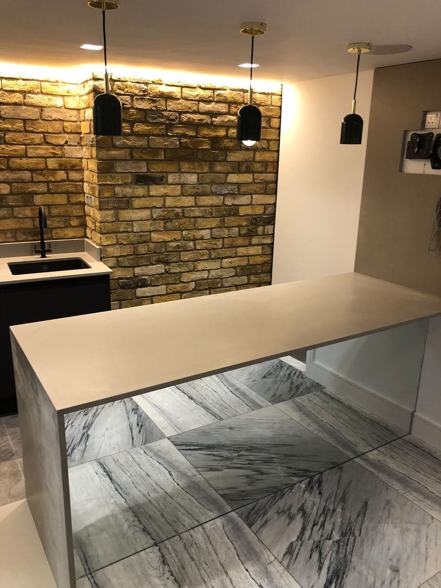 Kitchen bar with a marble waterfall edge and exposed brick