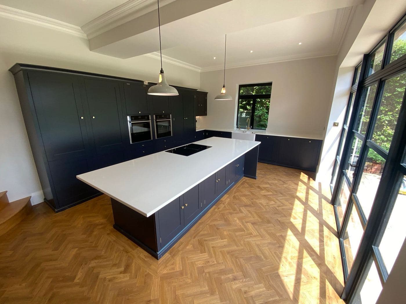 Kitchen island on a herringbone floor beside a glazed corner