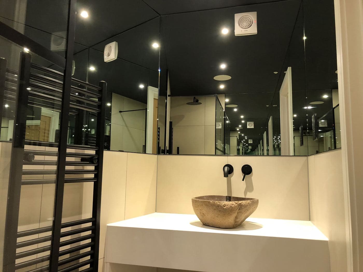En suite bathroom with a mirrored ceiling and freestanding tap