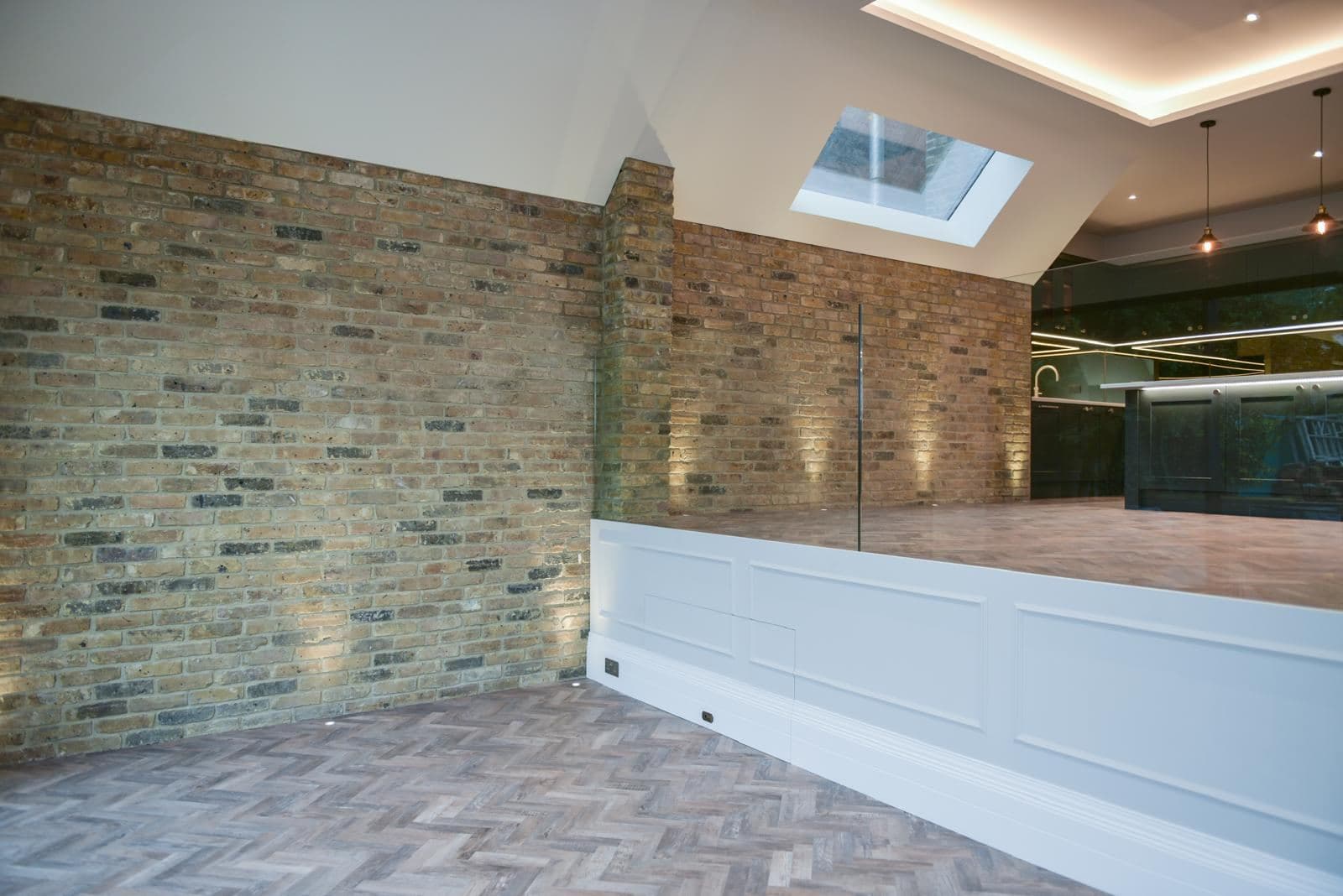 Exposed brick wall with lit panelling and herringbone floor