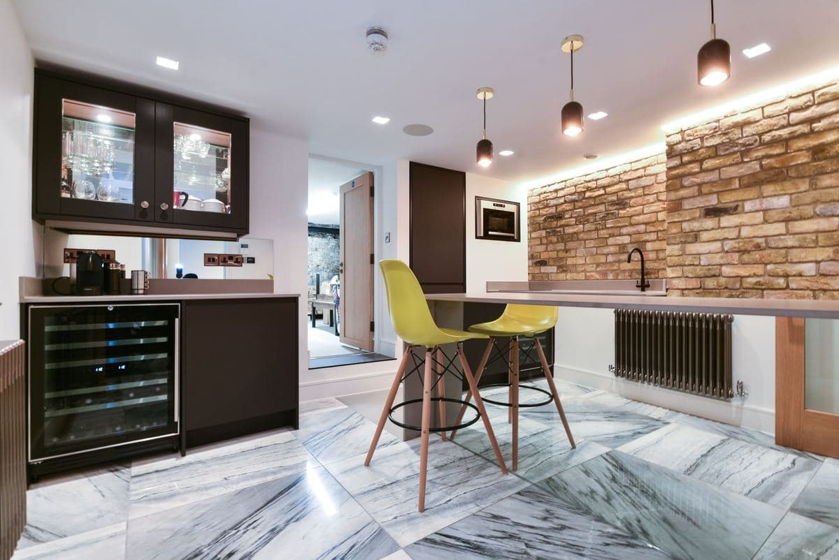 Kitchen bar with wine fridge and stools, brick feature wall