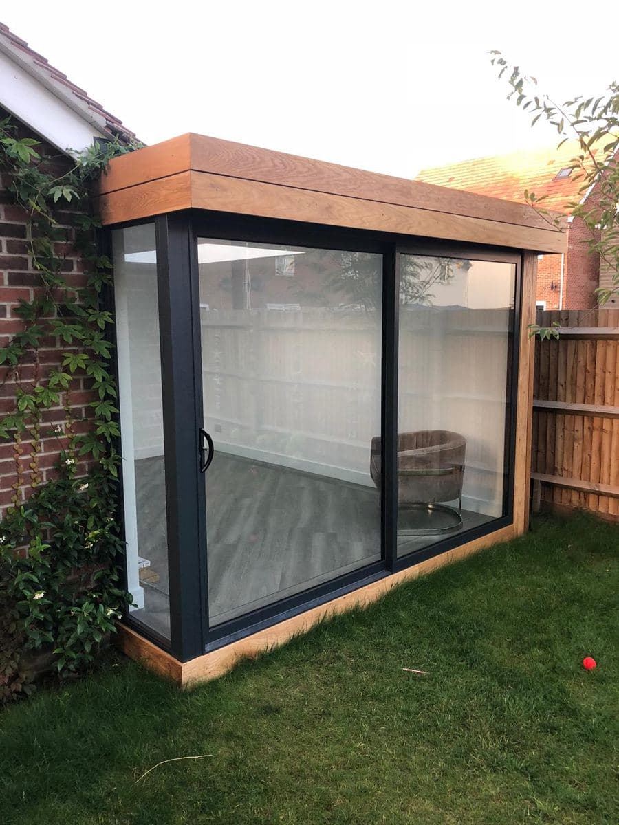 Brick garden room with sliding doors, seen across the lawn
