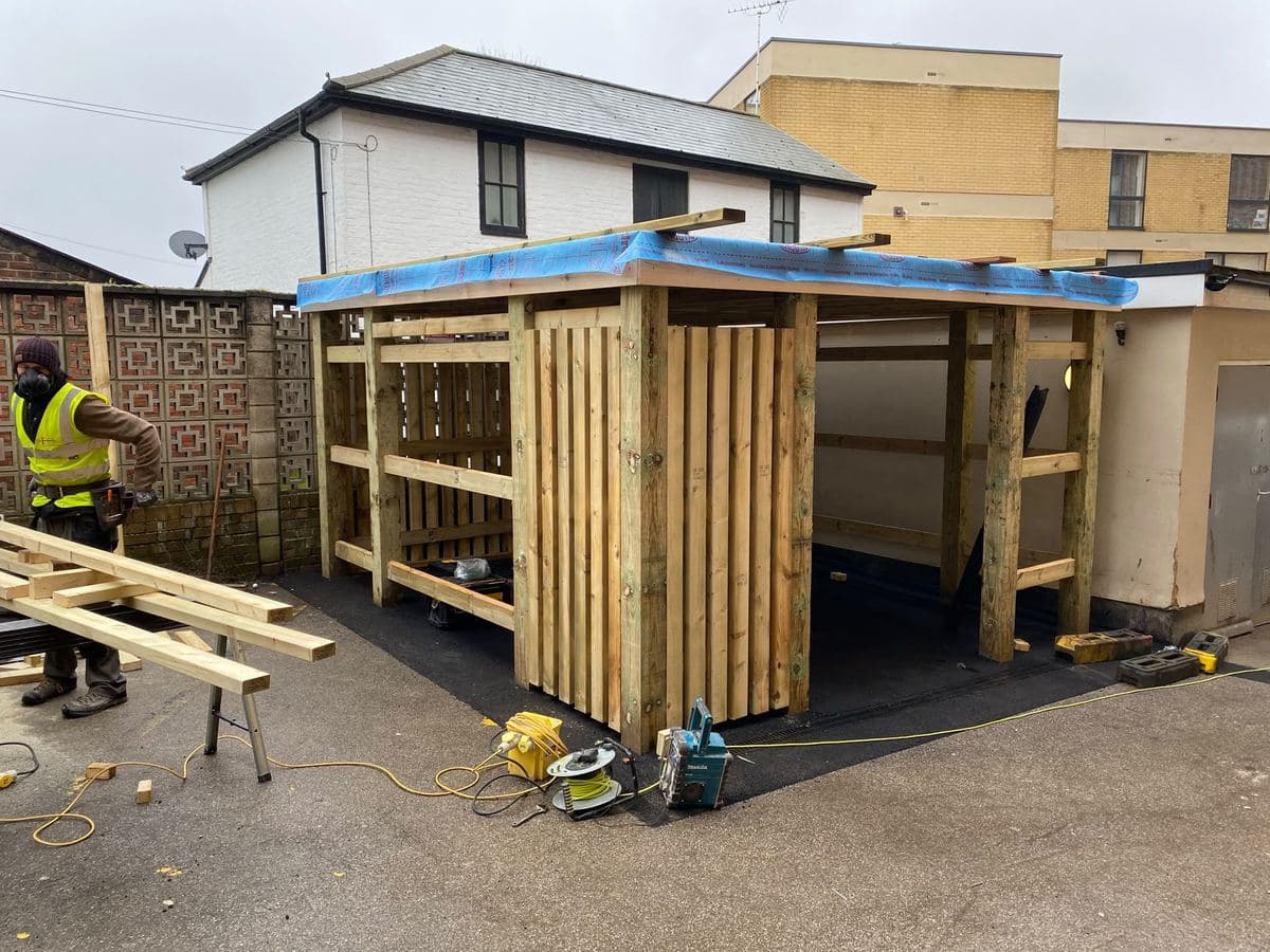 Decorative fret screen panels being fitted to a garden structure