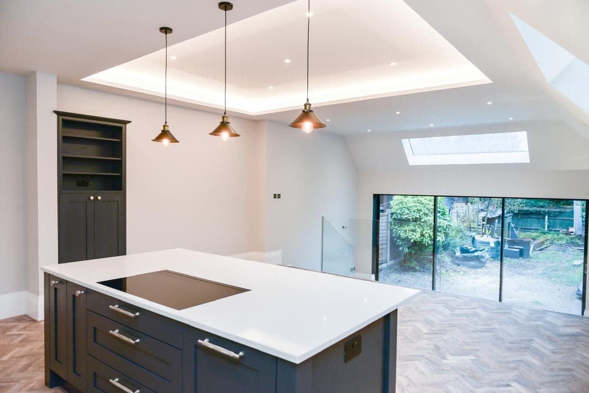 Navy kitchen with a rooflight, pendants and herringbone floor