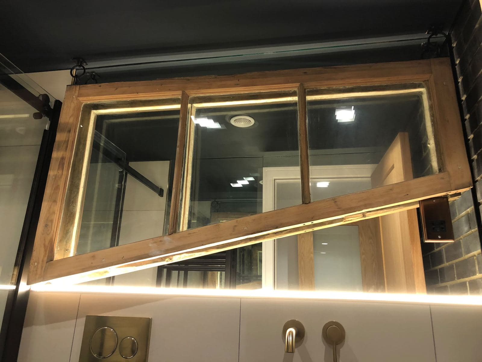 An old sash window rebuilt as an internal lit feature above a vanity
